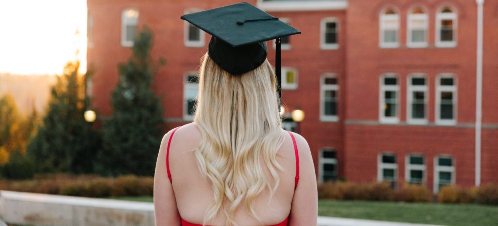 Jordan stands with her back to the camera in front of a building at WSU with a graduation hat on