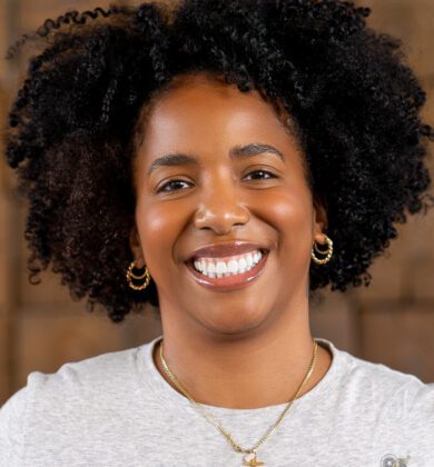 Dori is a Black woman with a curly hair, wearing a gray shirt