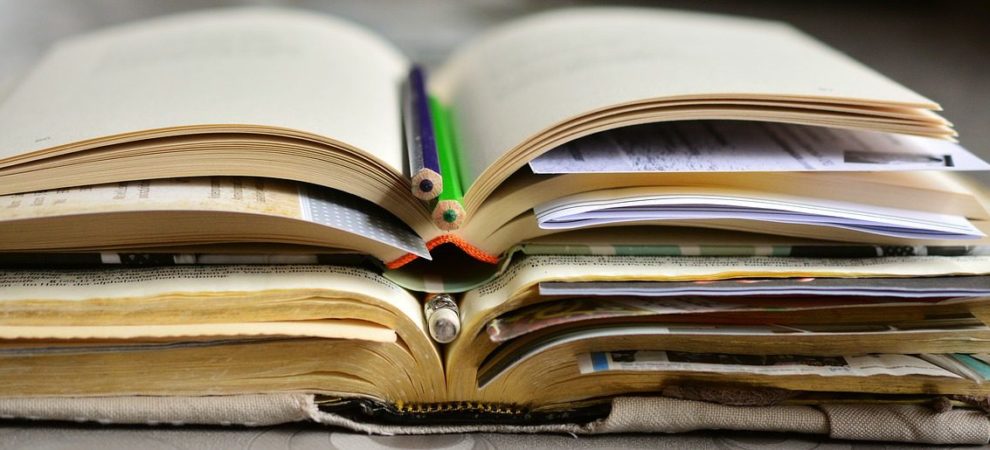 Open books with pencils marking the place lay stacked on each other