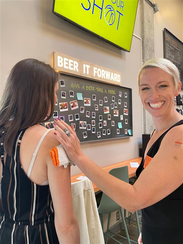 Two Minerva Strategies team members are giving each other fake tattoos.