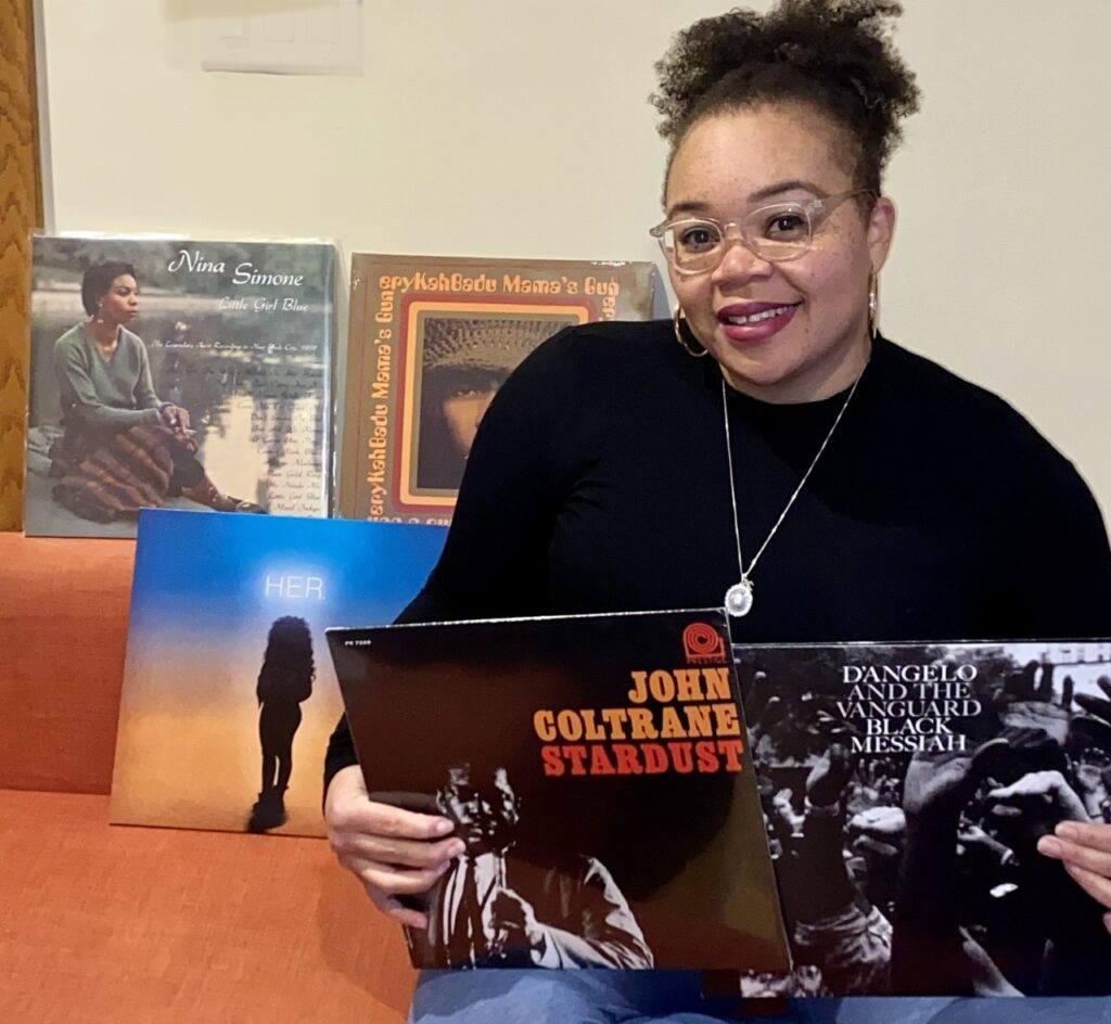Crystal, Minerva's Business Operations Associate, holding several record vinyls.