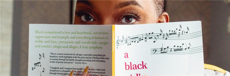 Kandice Head's eyes are visible above a book of her poetry that she is holding