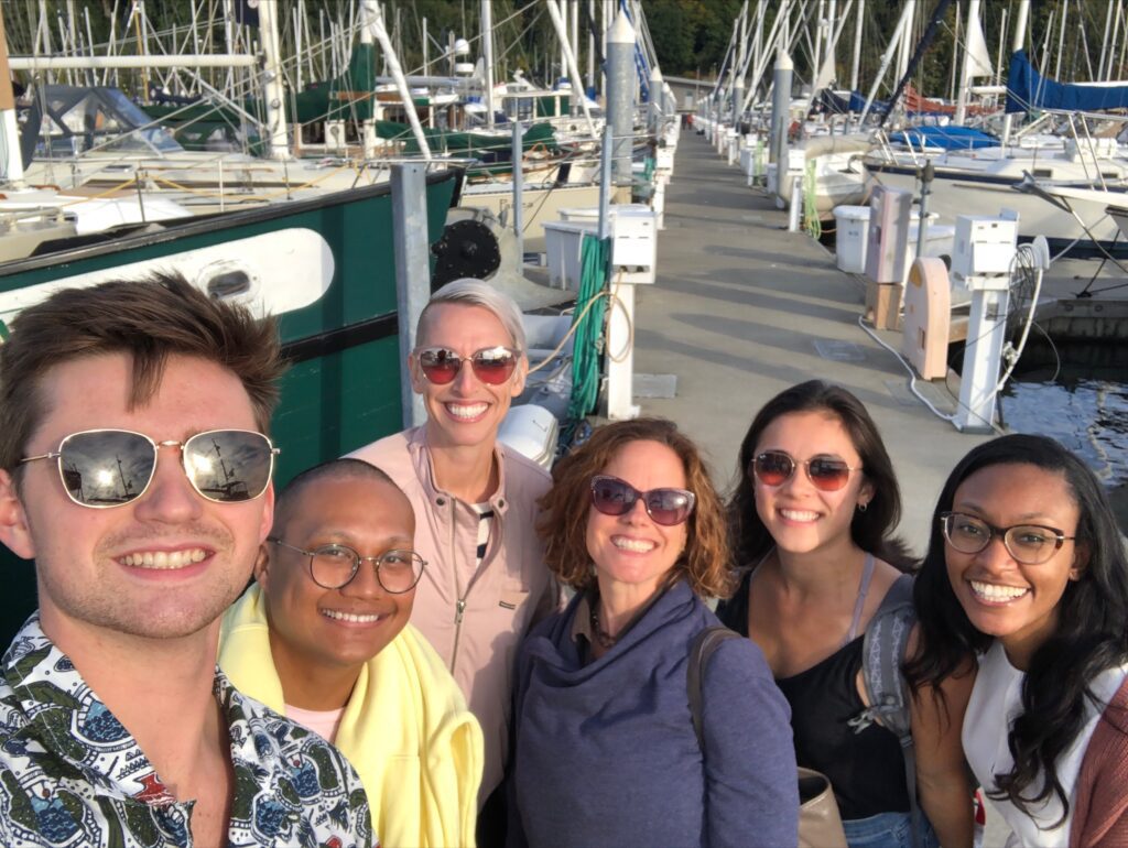 The Minerva team poses for a selfie surrounded by boats in the harbor of Elliot Bay