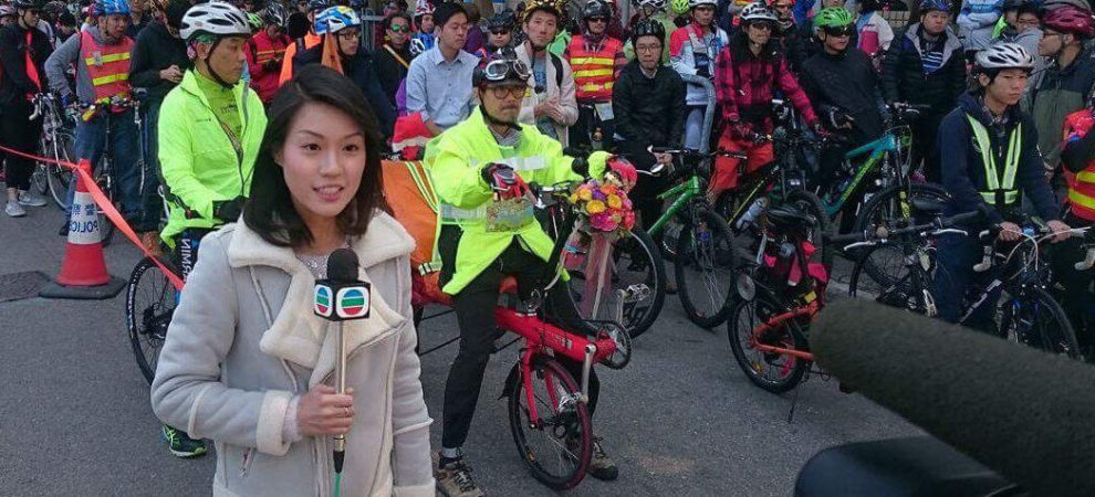 Rachel Yang stands on a street in Hong Kong with protestors, holding a reporters microphone