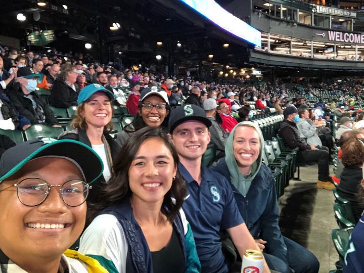The Minerva team smiles while sitting and watching the Mariners game