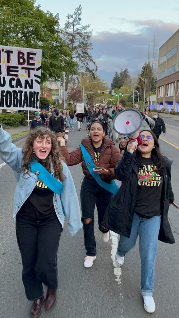 Kati and two friends marching in the Take Back the Night march in Eugene, Kati is holding a megaphone and shouting