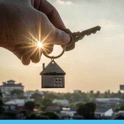 A close up image of a hand holding a key on a house-shaped keychain.