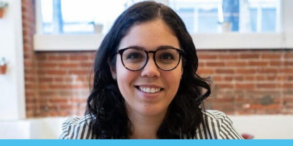 M wears glasses and a striped shirt and smiles 