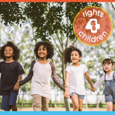 four children hold hands and smile