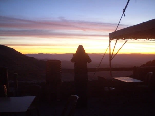 A person watches a desert sunrise.